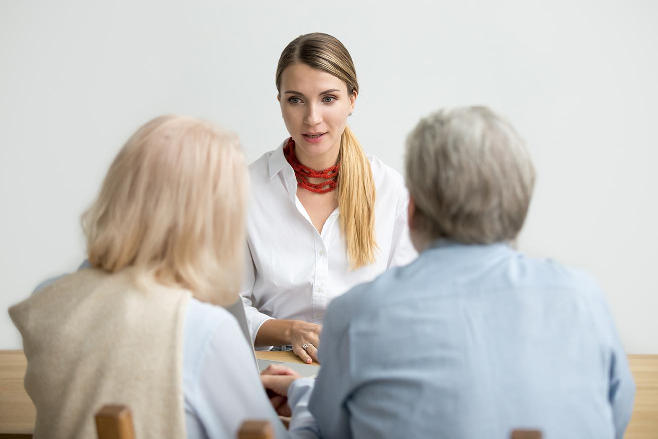 An insurance broker talking with two clients across a table